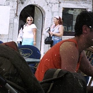 Woman sitting outdoors at café with cup.