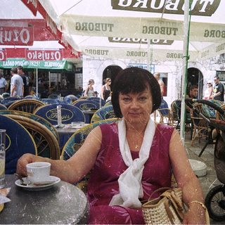 Woman sitting outdoors at café with cup.