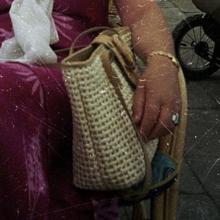 Woman sipping coffee outdoors under umbrellas.