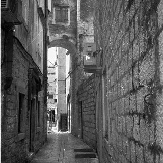 Narrow alleyway with stone walls and archway.
