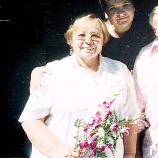 Four people posing together indoors with arms around each other.