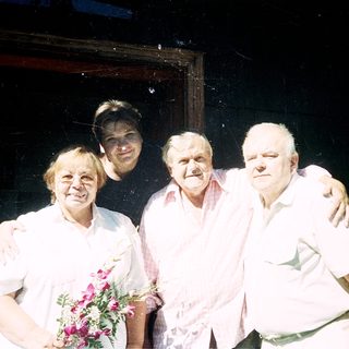 Four people posing together indoors with arms around each other.