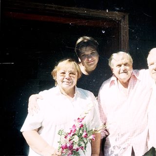 Four people posing together indoors with arms around each other.