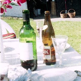 Man sitting outdoors at picnic table with drinks.