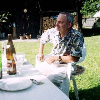Man sitting outdoors at picnic table with drinks.