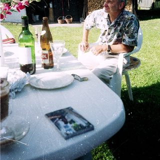 Man sitting outdoors at picnic table with drinks.