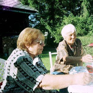 Three elderly women enjoying outdoor meal together.