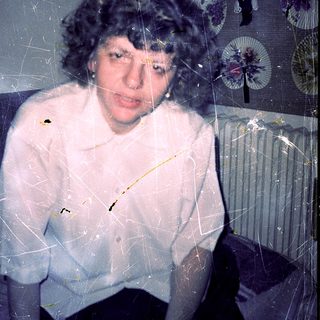 A person wearing a white sweater through frosted or cracked glass.