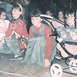 Displaced children in makeshift shelter with stroller.