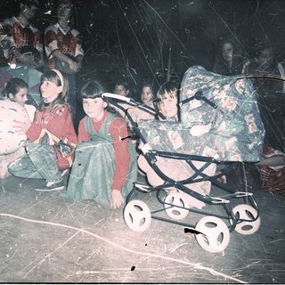Displaced children in makeshift shelter with stroller.