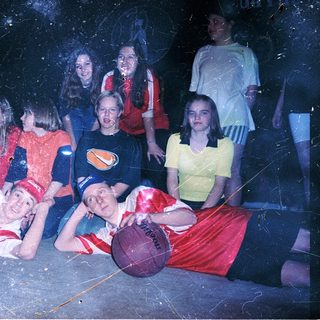 Group of people posing with basketballs indoors.