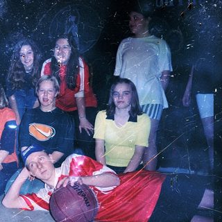 Group of people posing with basketballs indoors.