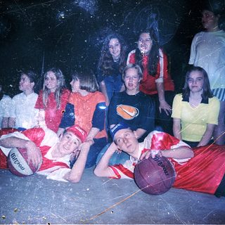 Group of people posing with basketballs indoors.