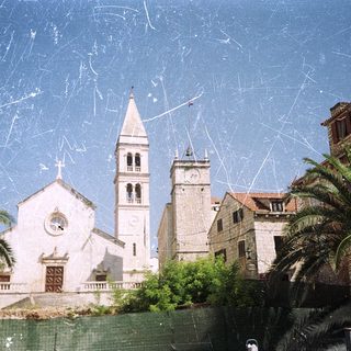 Medieval church with bell tower, surrounded by palm trees.
