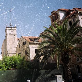 Medieval church with bell tower, surrounded by palm trees.