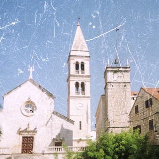 Medieval church with bell tower, surrounded by palm trees.