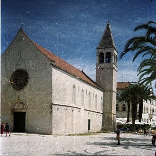 Romanesque church with bell tower in Mediterranean plaza.