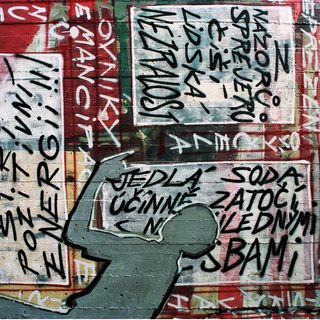 Graffiti-covered wall with Czech slogans and handwritten text.
