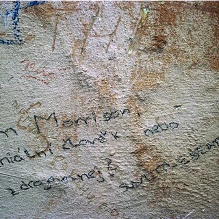 Graffiti inscription on weathered stone wall.