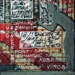 Graffiti-covered wall with Czech slogans and stickers.