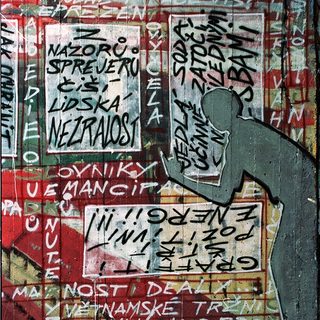 Graffiti-covered wall with Czech slogans and stickers.