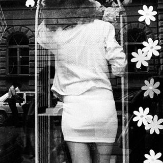 A person decorates a school window display with flower cutouts.