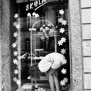 Window display decoration with floral cutouts and a mannequin in a shop window.