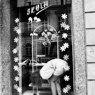 Window display decoration with floral cutouts and a mannequin in a shop window.