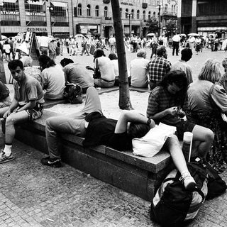 People resting on a bench in a busy city square.