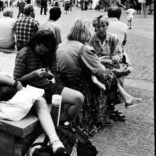 People resting on a bench in a busy city square.