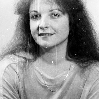 Wet-haired woman smiling in black-and-white photo.