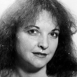 Woman with curly hair, neutral expression.