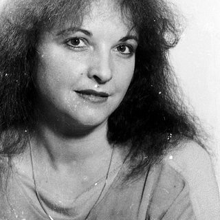 Woman with curly hair, neutral expression.
