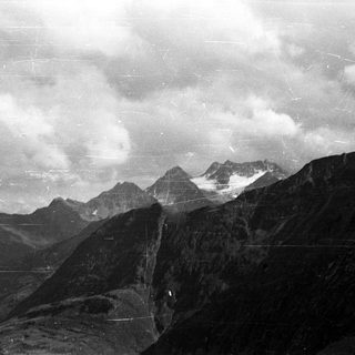 Mountainous landscape with snow-capped peaks and cloudy sky.
