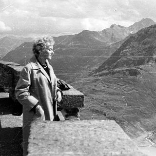 Woman standing on mountain ridge overlooking rugged peaks.