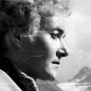 Woman standing by railing overlooking mountainous landscape.