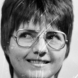 Wet-haired woman smiling with glasses.
