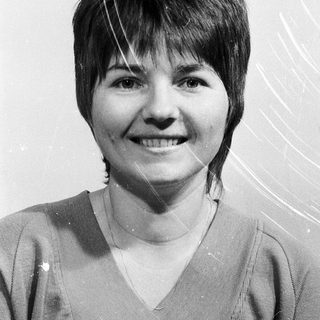 Smiling woman with short hair in casual blouse.