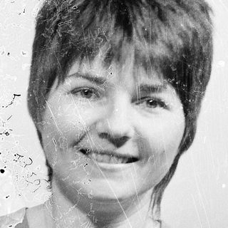 Short-haired woman smiling in vintage-style black-and-white photo.