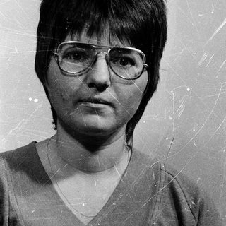 Black-and-white portrait of a woman wearing glasses.