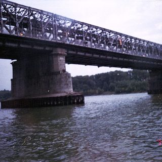Steel railway bridge over water with crowd.