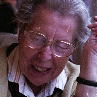 Elderly woman smiling by train window.