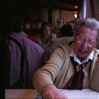 Elderly woman smiling by train window.