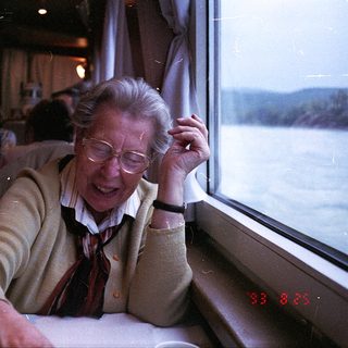 Elderly woman smiling by train window.