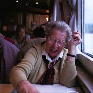 Elderly woman smiling by train window.