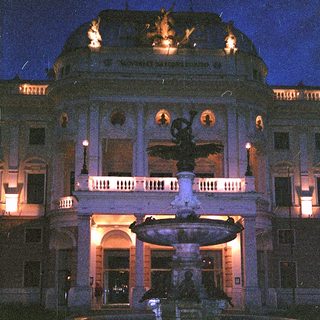 Elegant building with illuminated fountain at night.