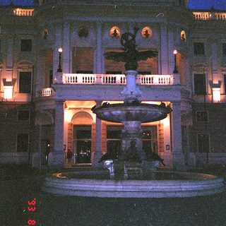 Elegant building with illuminated fountain at night.