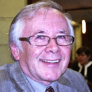 Elderly man smiling indoors at a café.