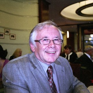 Elderly man smiling indoors at a café.