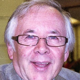 Man in suit smiling indoors at event.